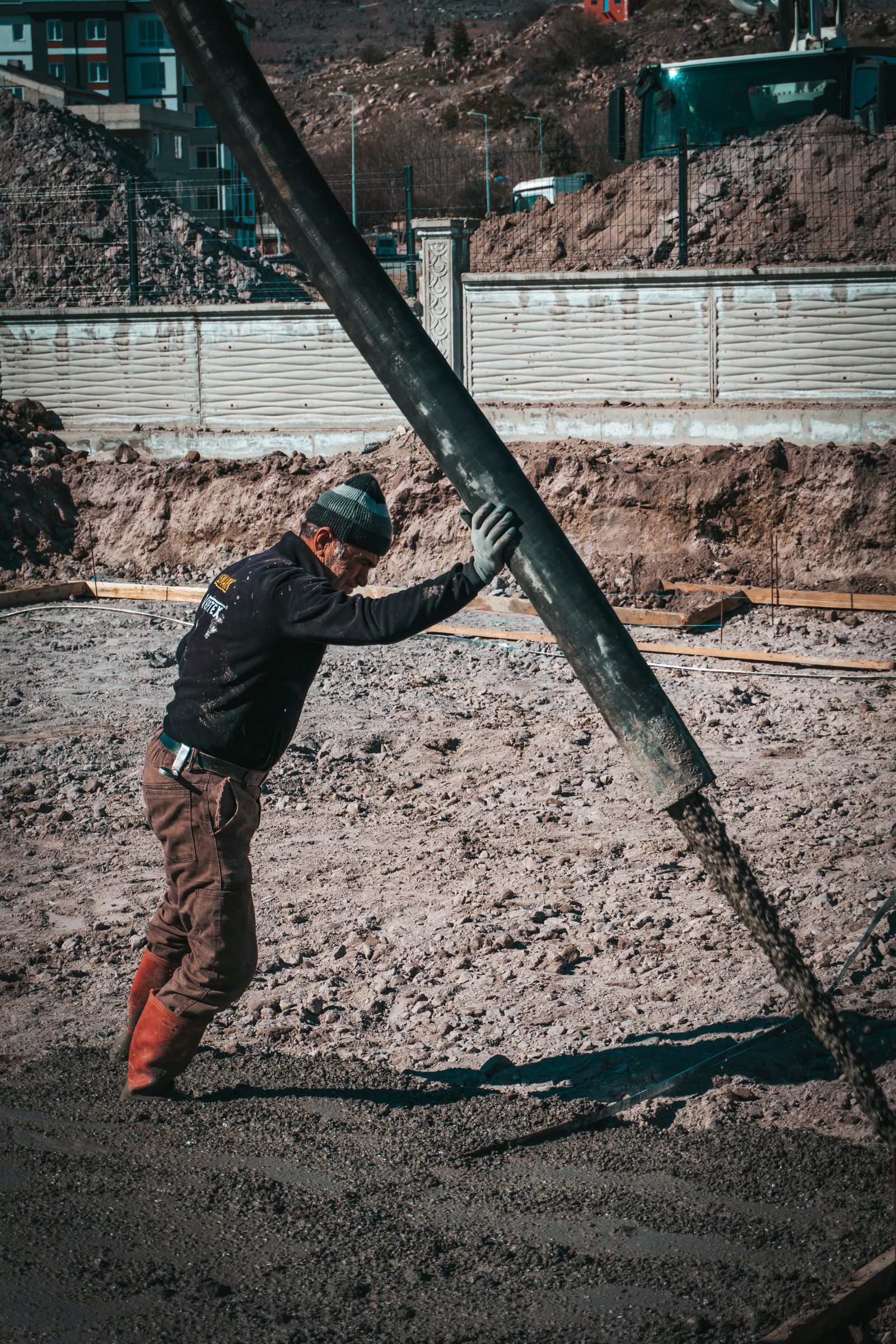 Şantiyede perde kalıbına beton basan işçi